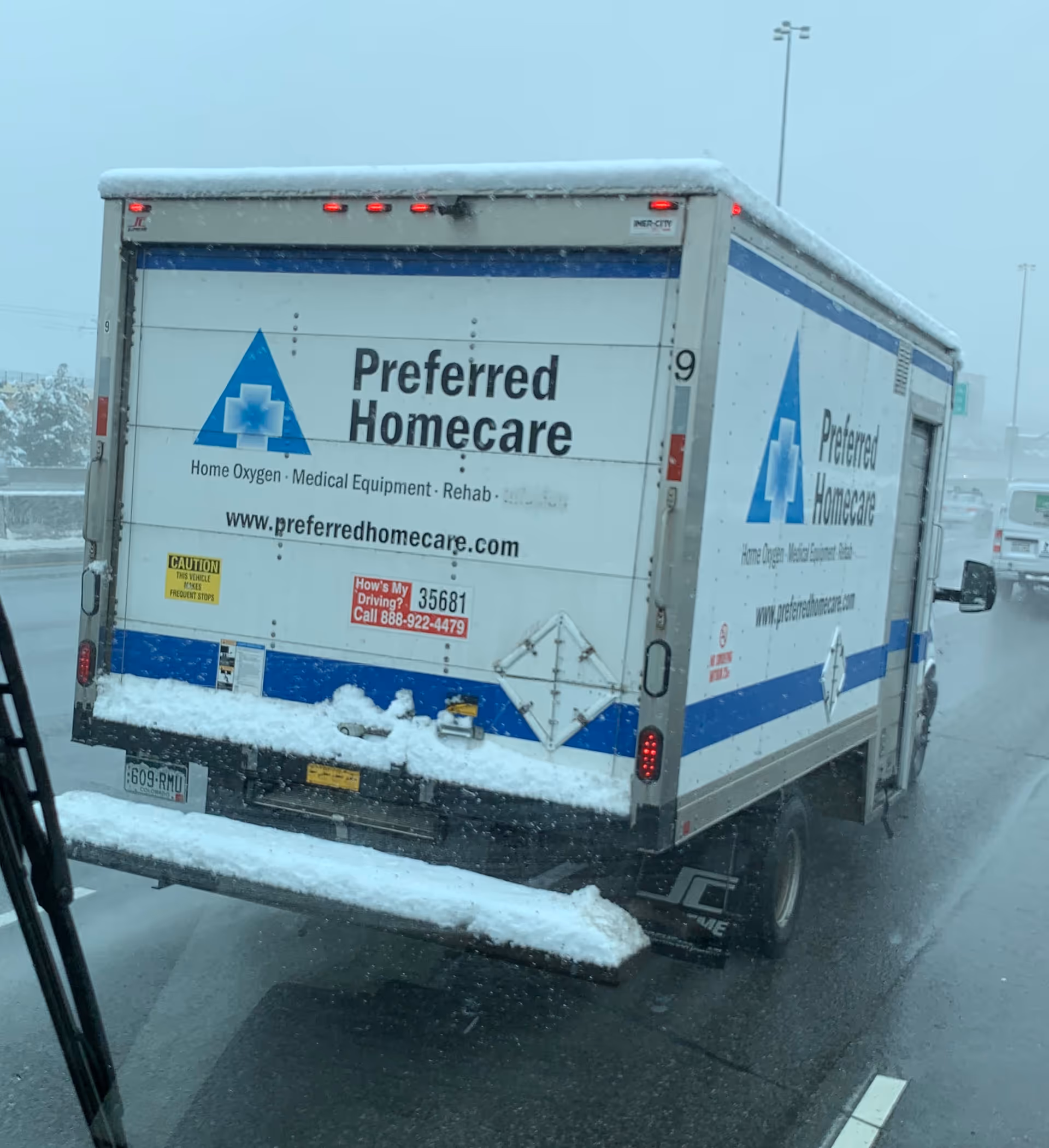 Rear view of a Preferred Homecare delivery truck on a snowy highway.