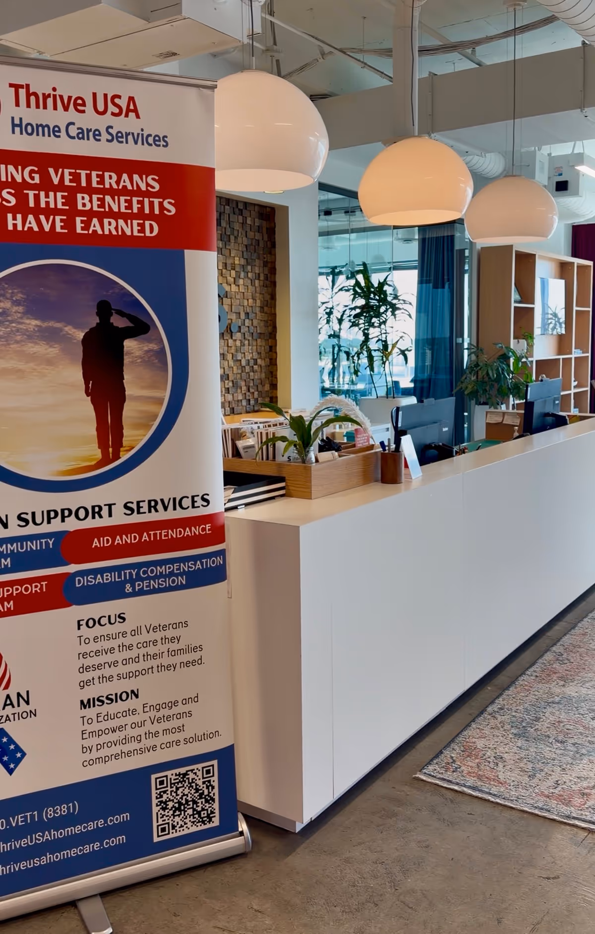 Interior reception area featuring Thrive USA banner, white counter, and hanging pendant lights.