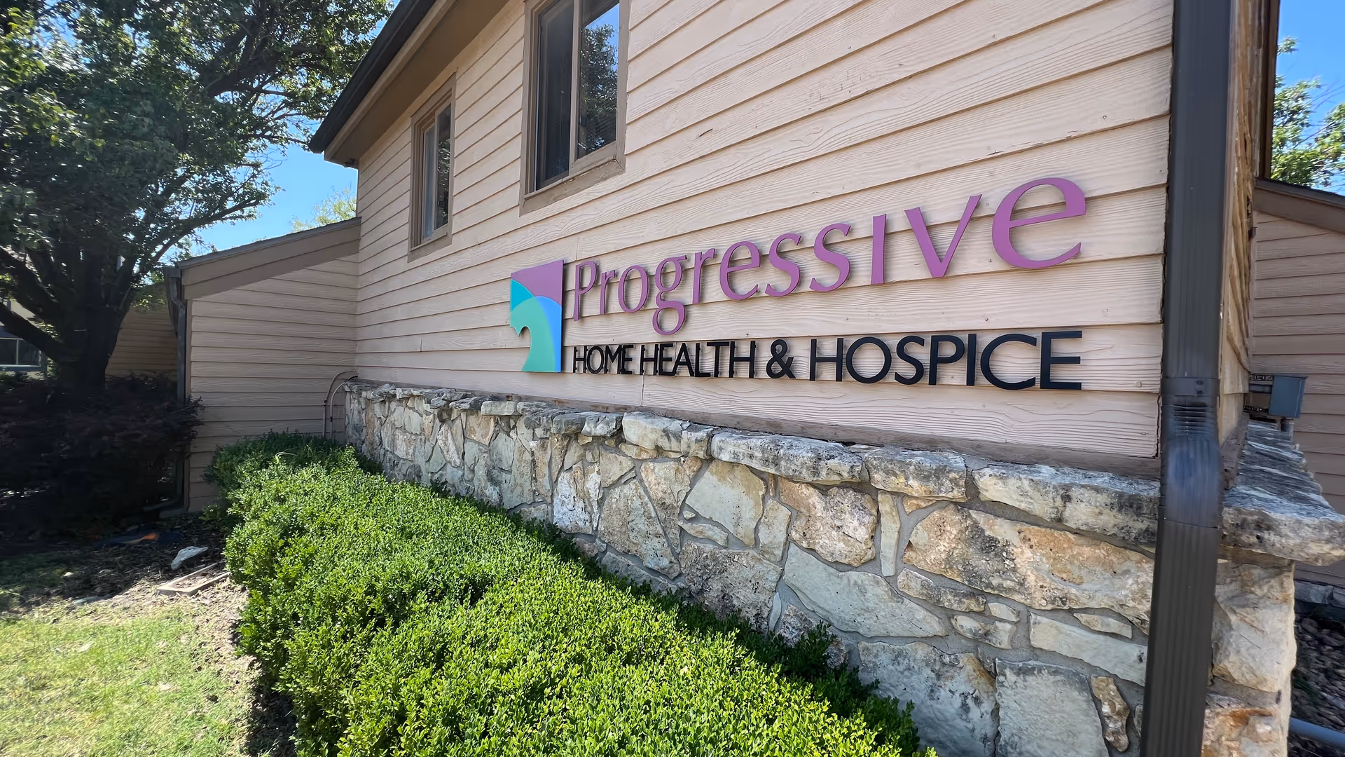 Exterior view of Progressive Home Health and Hospice building with stone foundation and landscaping.