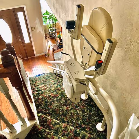 Interior staircase with a white stairlift chair attached to the railing