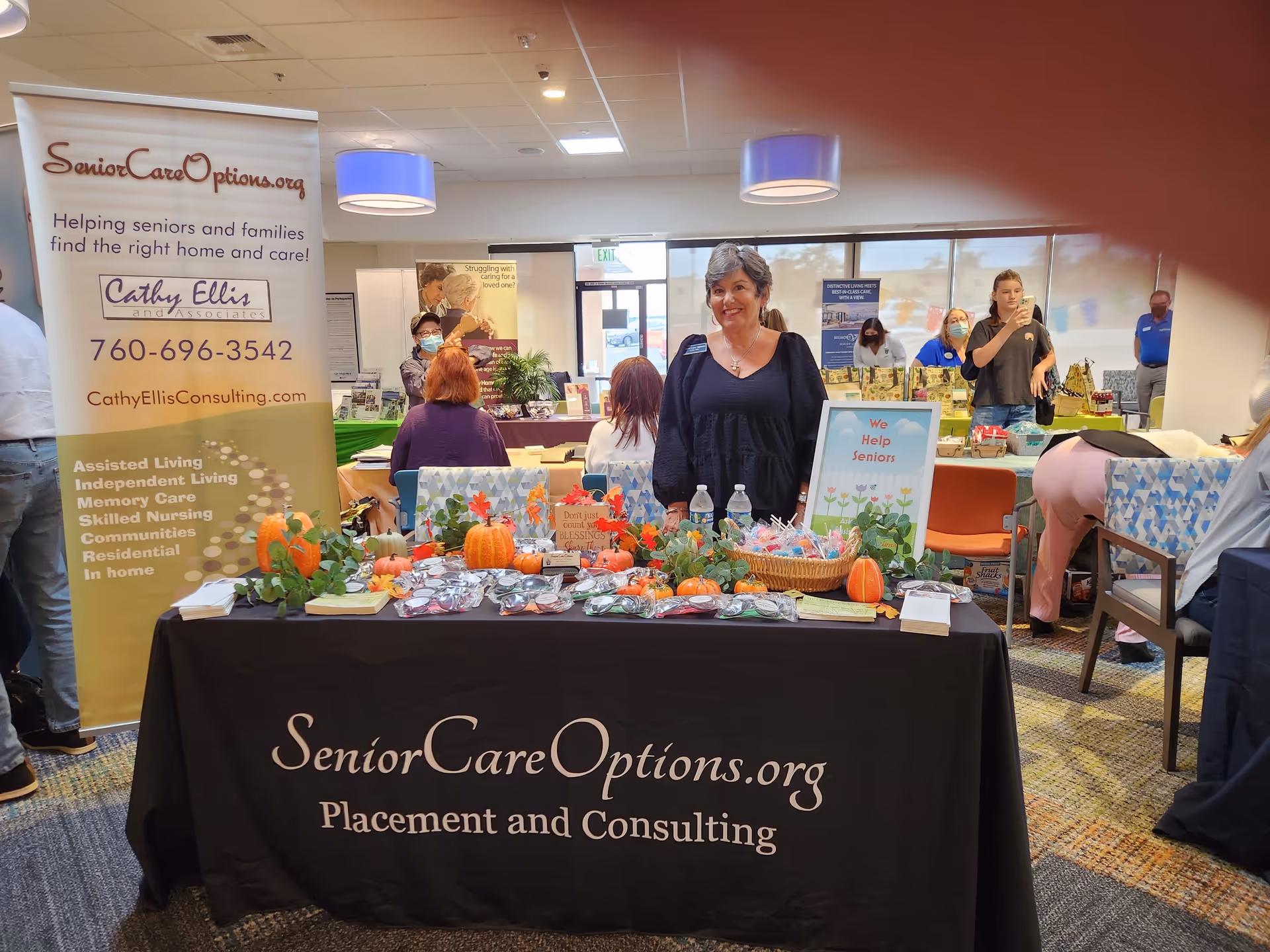 Indoor senior care information booth with banners, staff, and table.