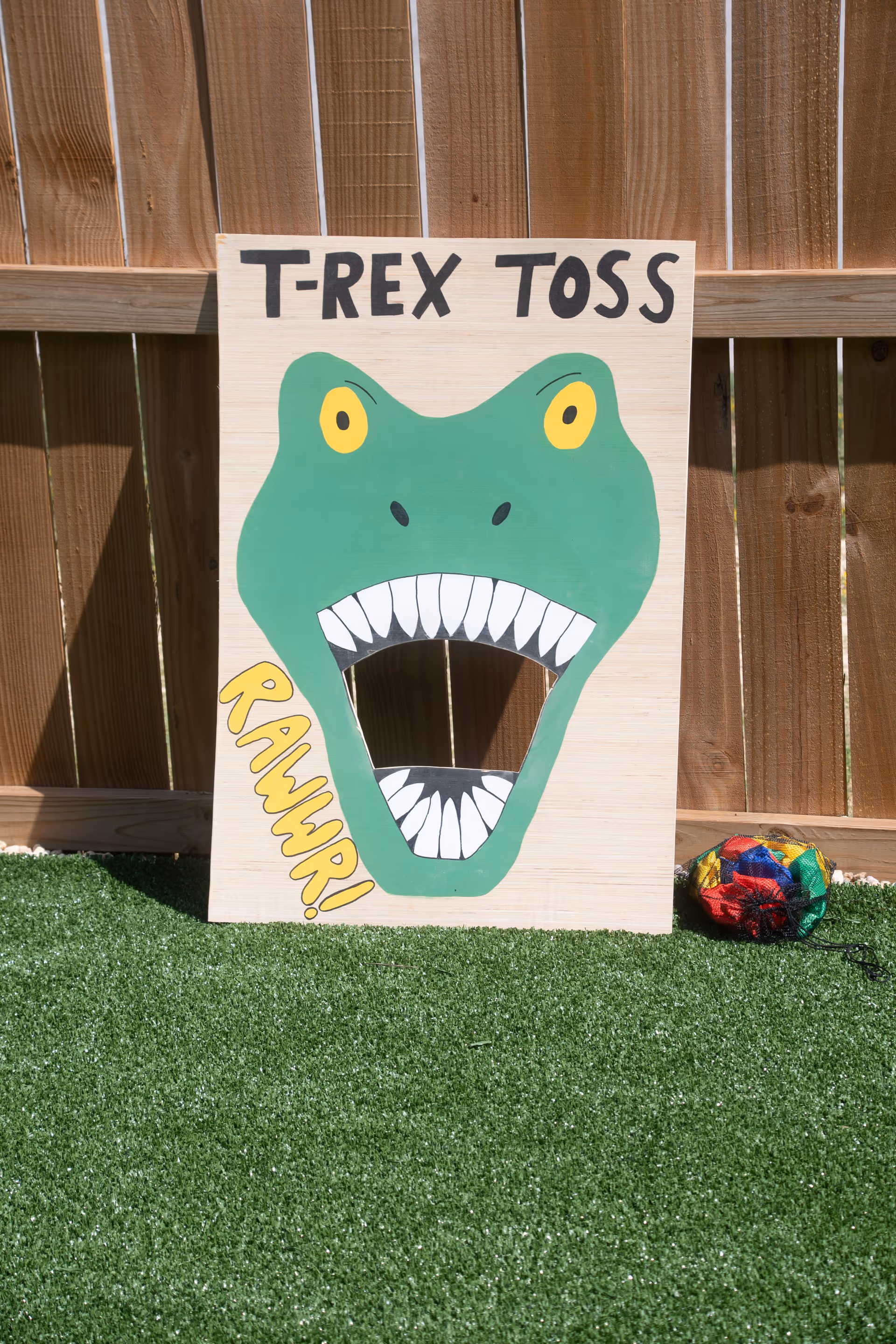 Outdoor yard featuring a T-Rex Toss sign cutout on artificial grass.