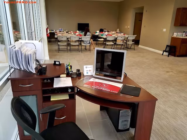 Reception desk with computer and documents in foreground; dining tables and chairs in background.