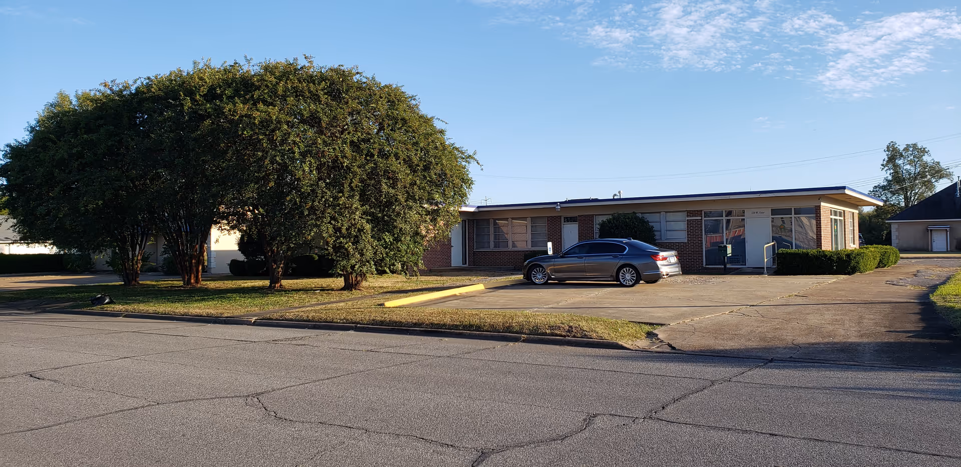 Front exterior of a single-story senior living facility with a car in the parking lot.