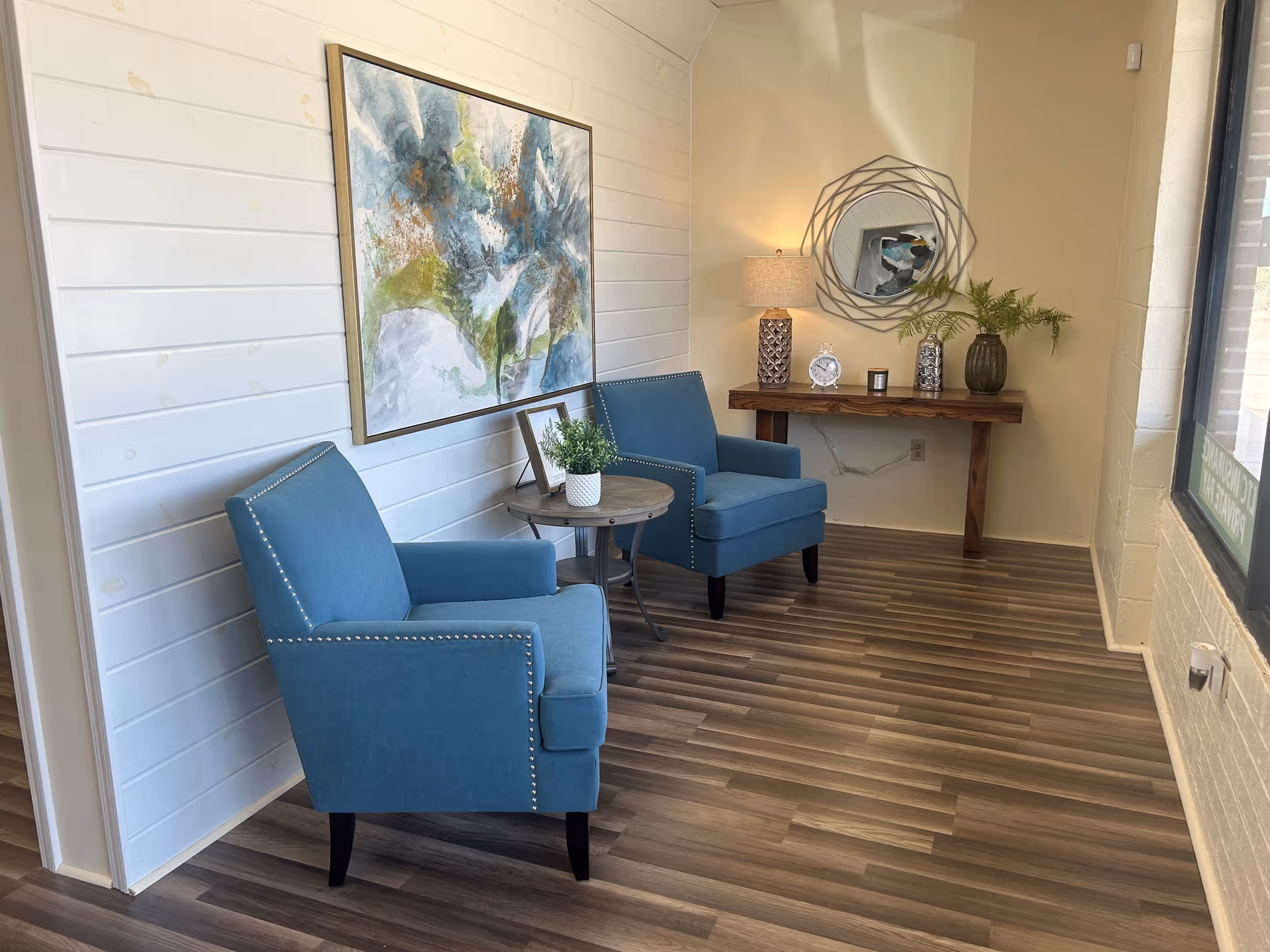 Two blue armchairs sit beside a round table in a bright, contemporary lounge.