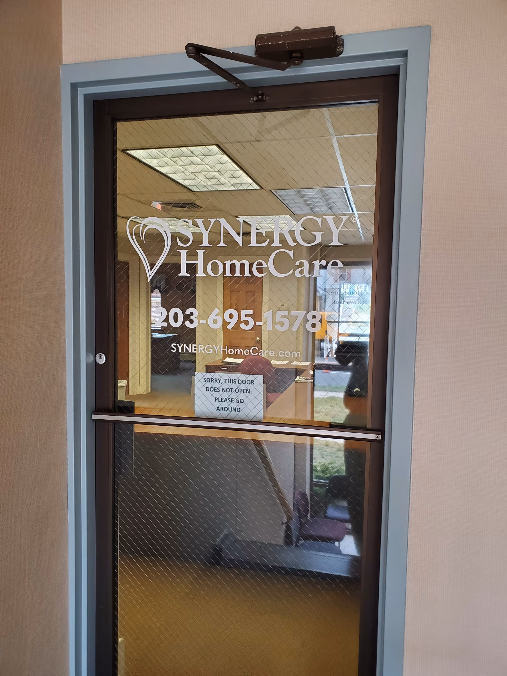 Glass door shows Synergy HomeCare logo; interior lobby visible beyond.