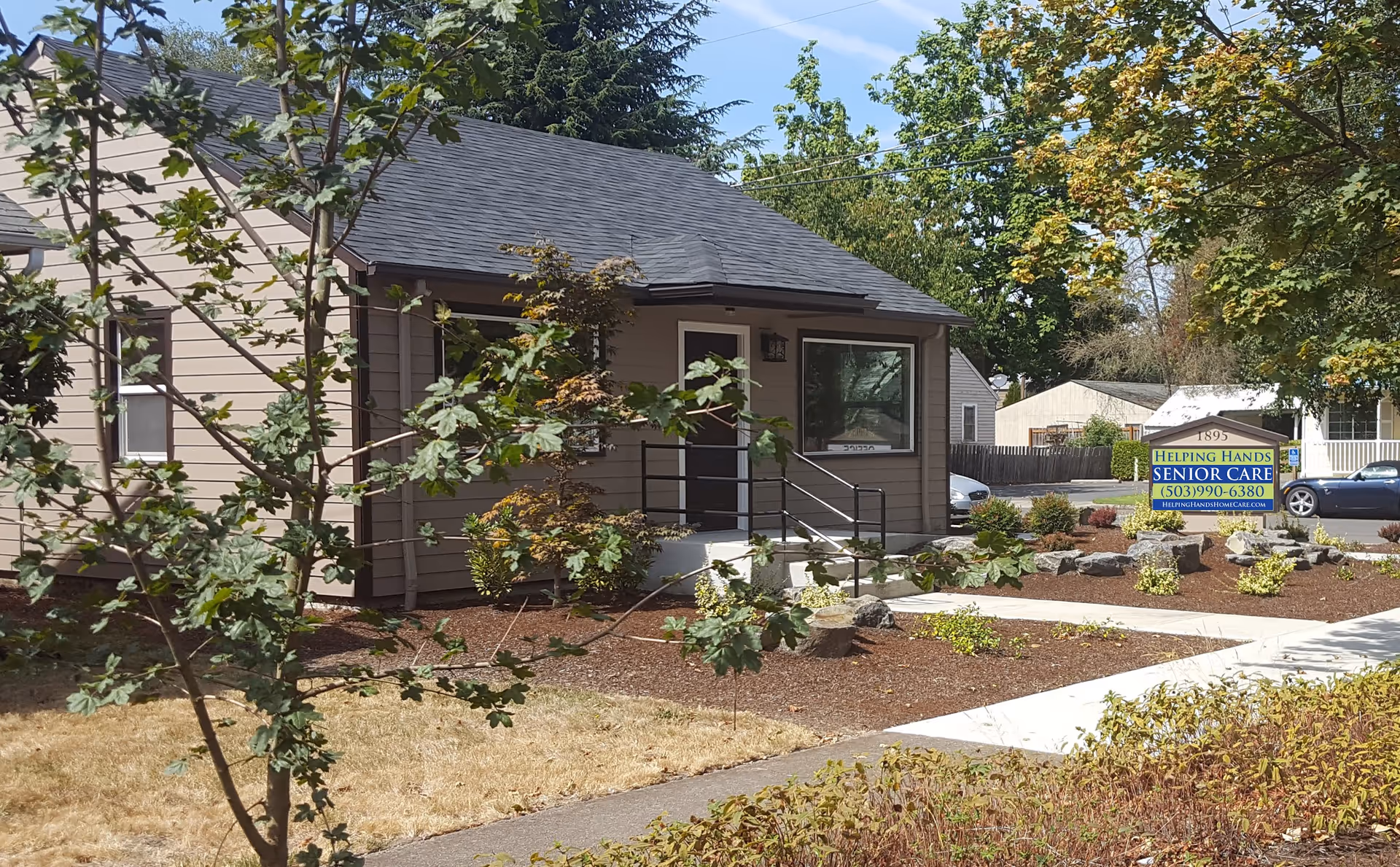 A small, single-story building with a ramp, landscaping, and a senior care sign in front.