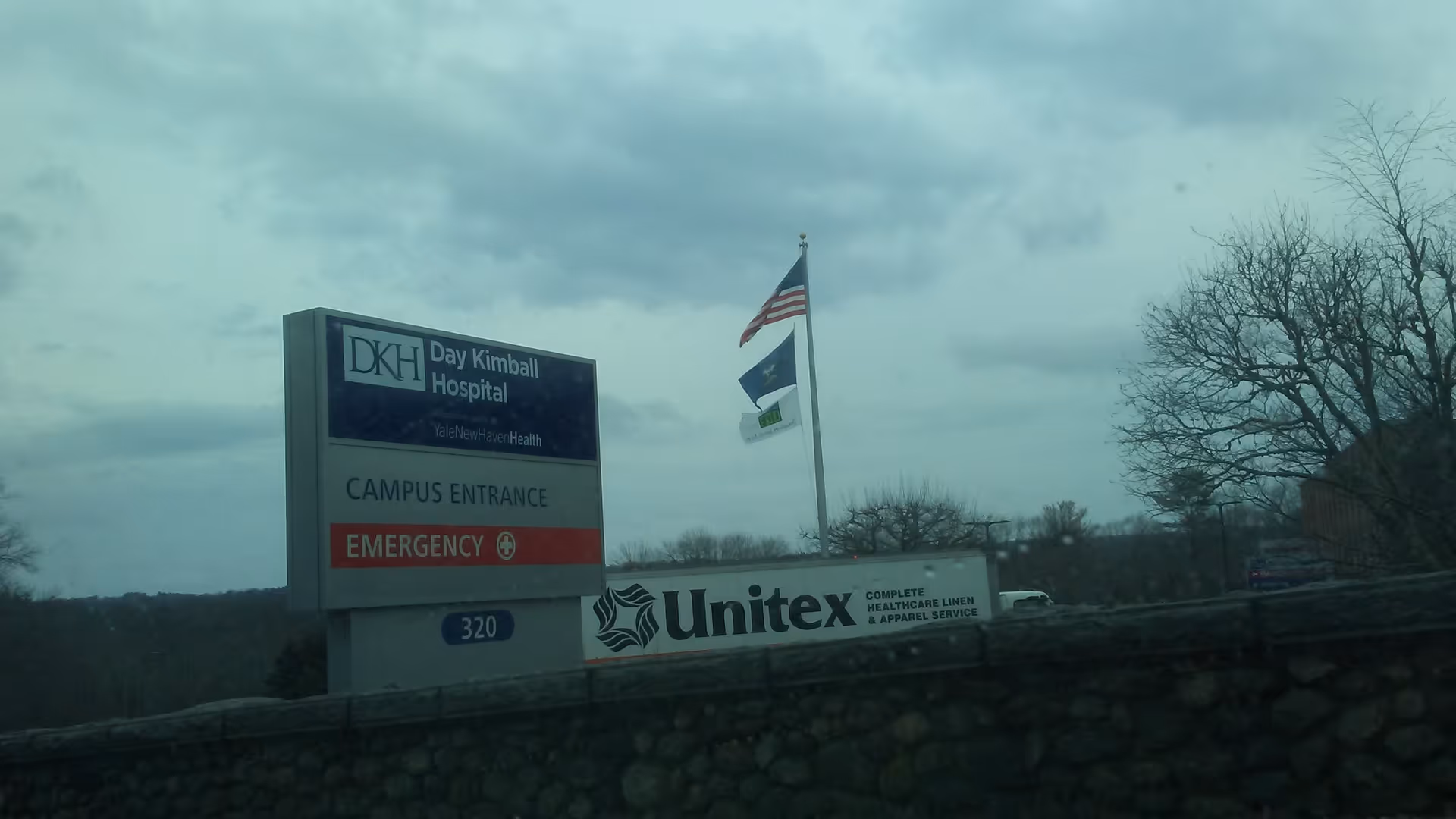 Exterior view of Day Kimball Healthcare campus entrance with signs, flags, and bare trees.