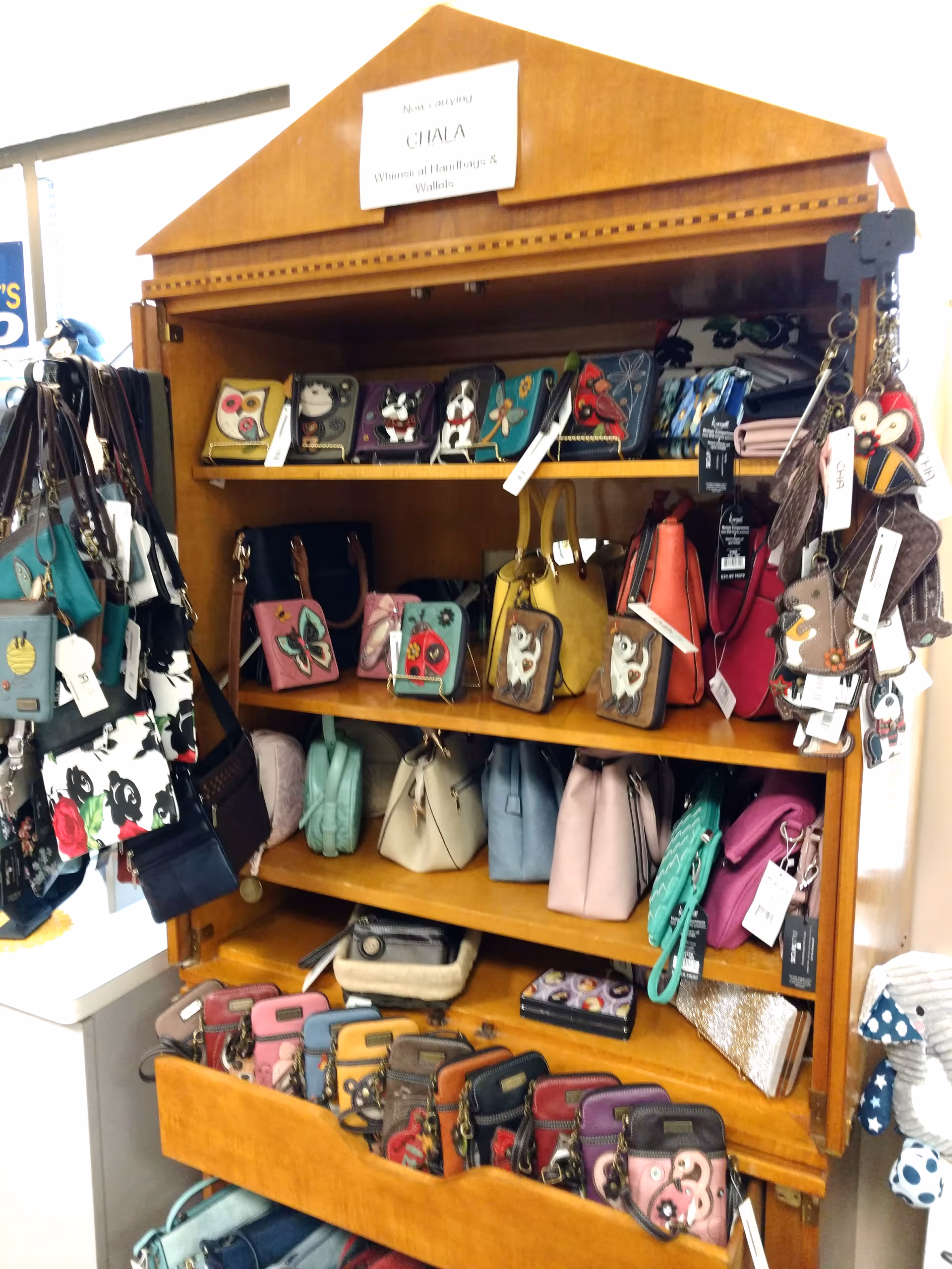 Indoor wooden display shelf filled with colorful wallets and purses.