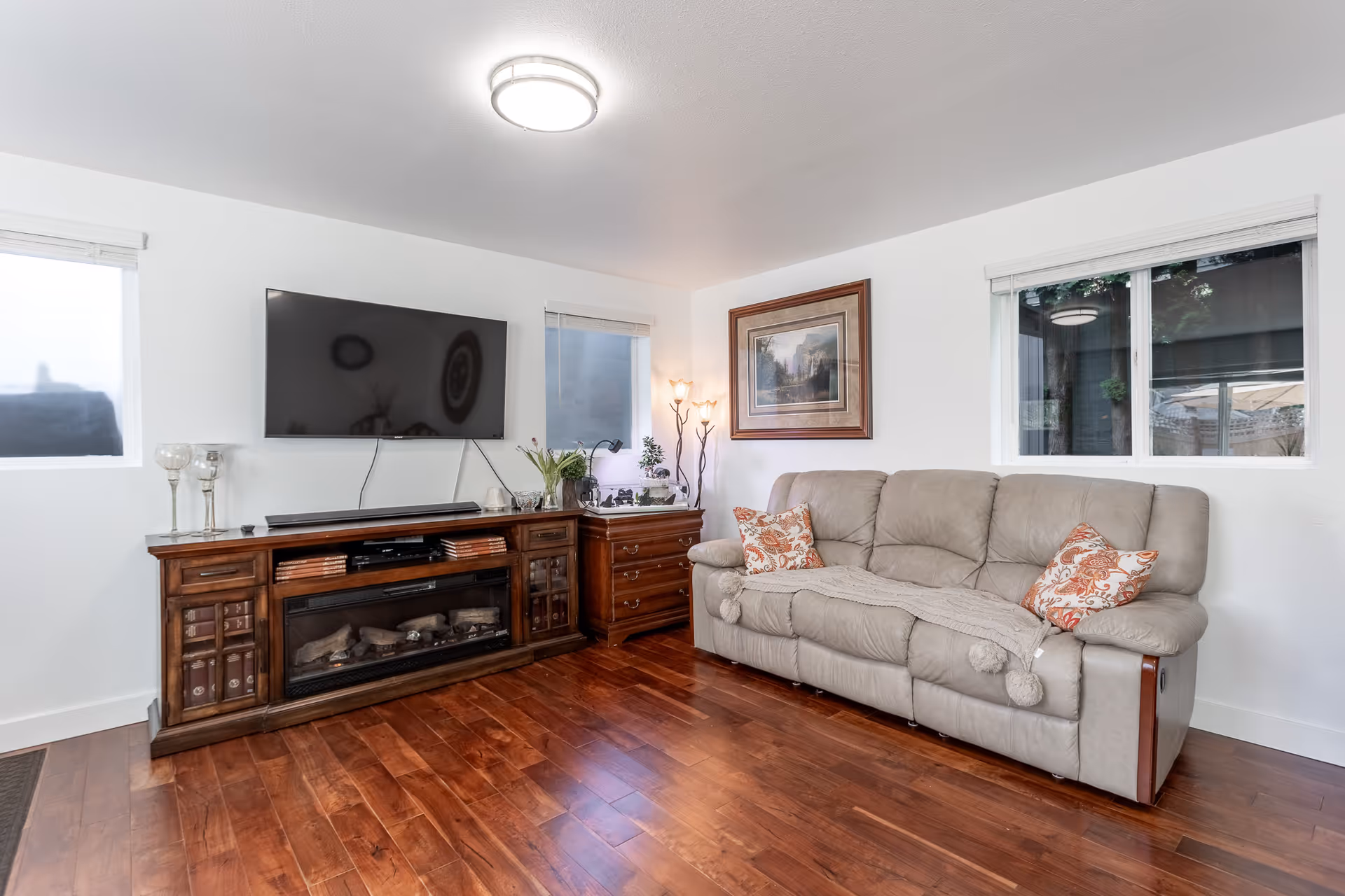 Cozy living room with sofa, wooden entertainment cabinet, TV, and framed art.