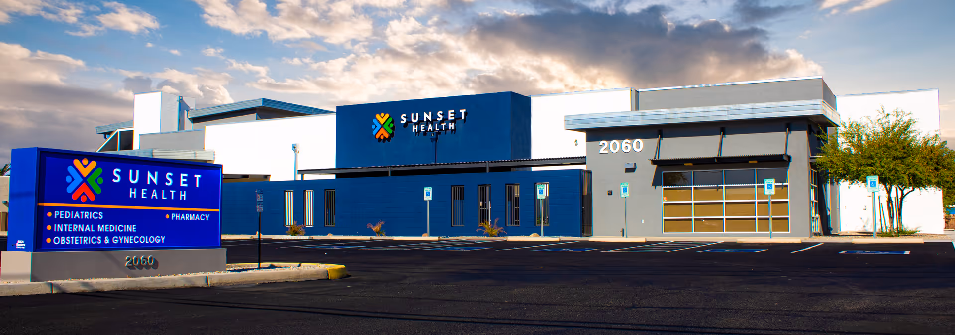 Exterior view of Sunset Health Inc building with blue signage and a parking lot.
