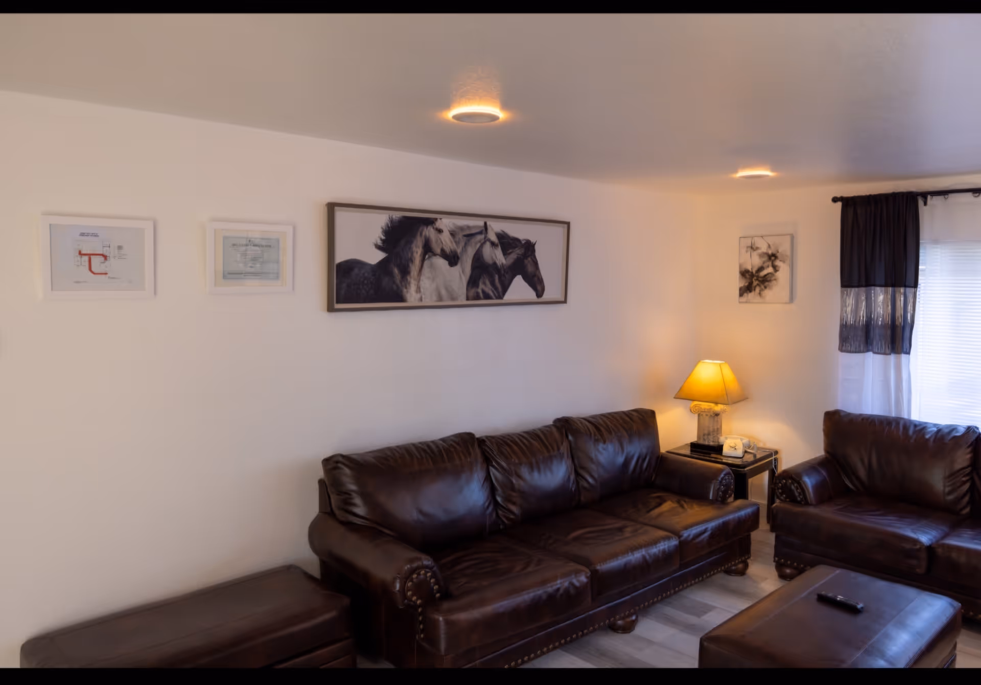 Cozy living room with brown leather sofas, coffee table, lamp, and wall art.