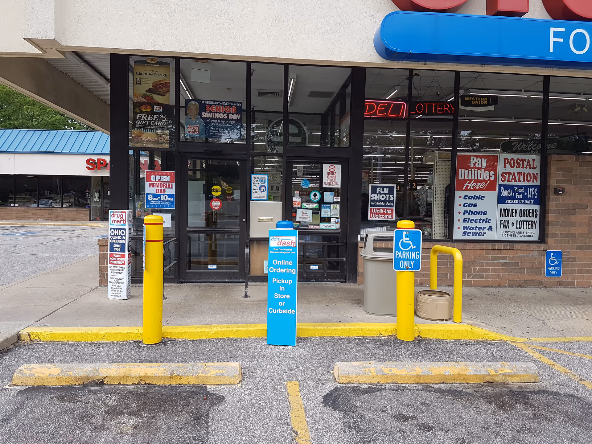 Front of Discount Drug Mart storefront with glass doors and parking lot.