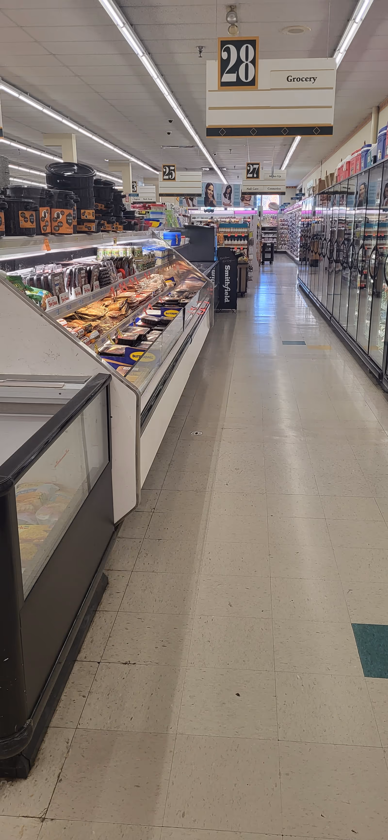A long Discount Drug Mart grocery aisle with refrigerated displays and overhead signs.