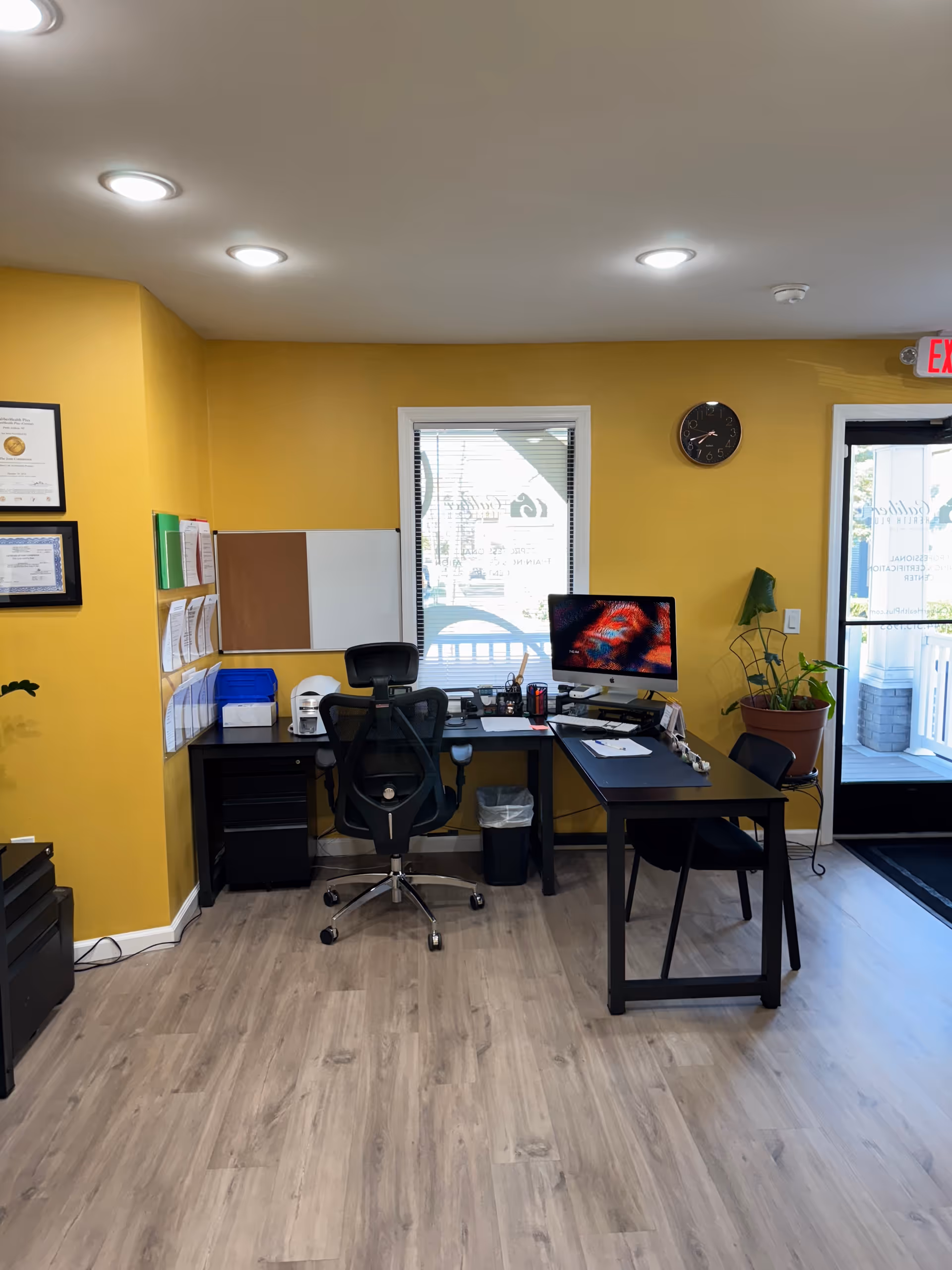 Bright yellow-walled office with desk, chair, and computer in administration area.