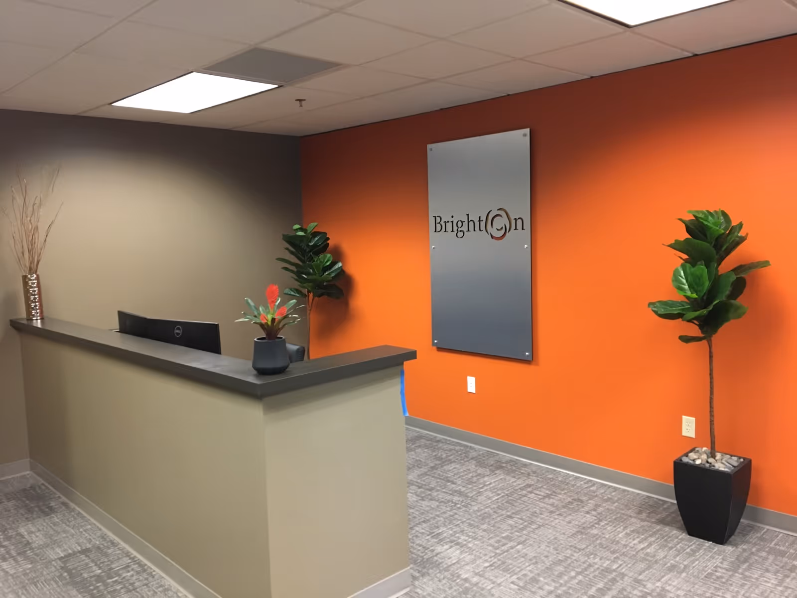 Brighton Hospice Eugene lobby with a reception desk, orange wall, and plants.