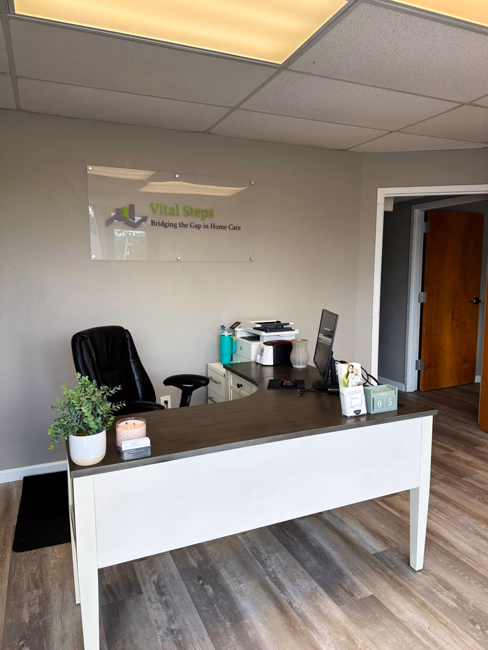 Reception desk in Vital Steps Home Care office with computer and signage.