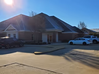 Front exterior view of Enhabit Home Health facility with parked cars and clear sky.