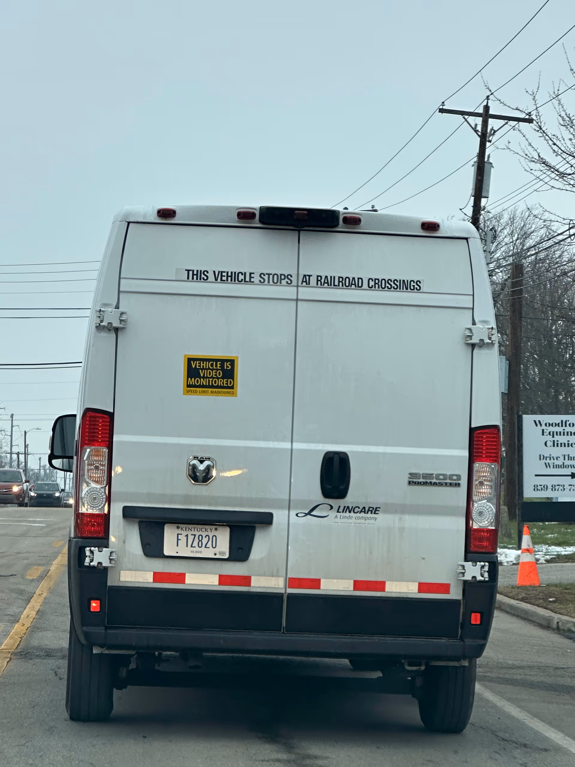 Rear view of a white Lincare van on a street with closed back doors.