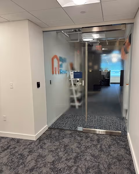 Glass doorway opens to a modern interior hallway with Right at Home branding.