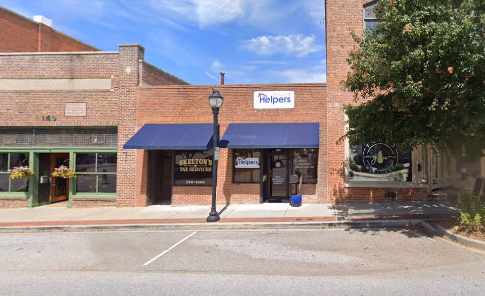 Brick storefronts along a street with a blue awning and Senior Helpers sign