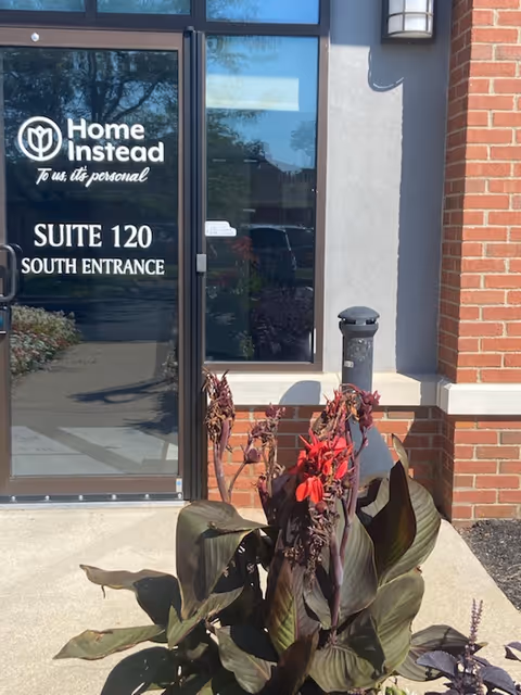 Exterior view of Home Instead entrance with glass door and brick facade.
