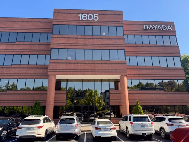 Exterior of BAYADA building with brick facade, large windows, and parked cars.