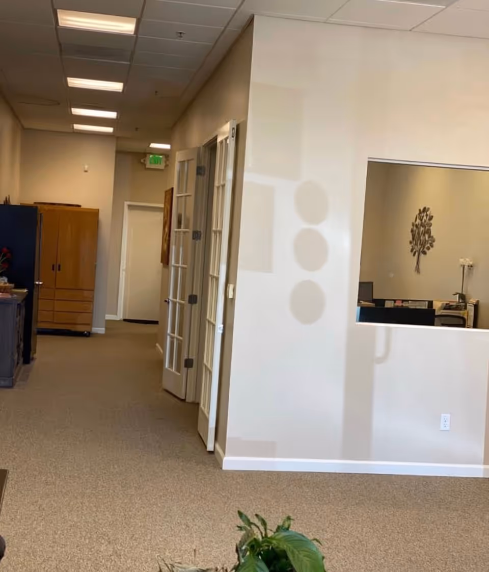 Interior hallway of a senior living facility with doors and a potted plant