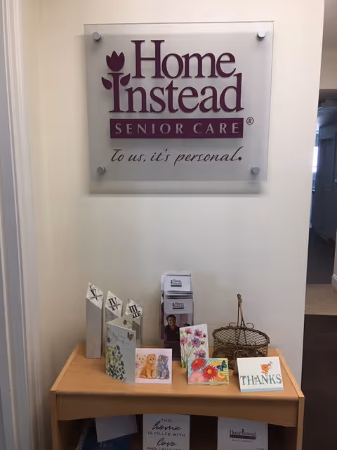 Indoor hallway with a Home Instead sign and a table of greeting cards.