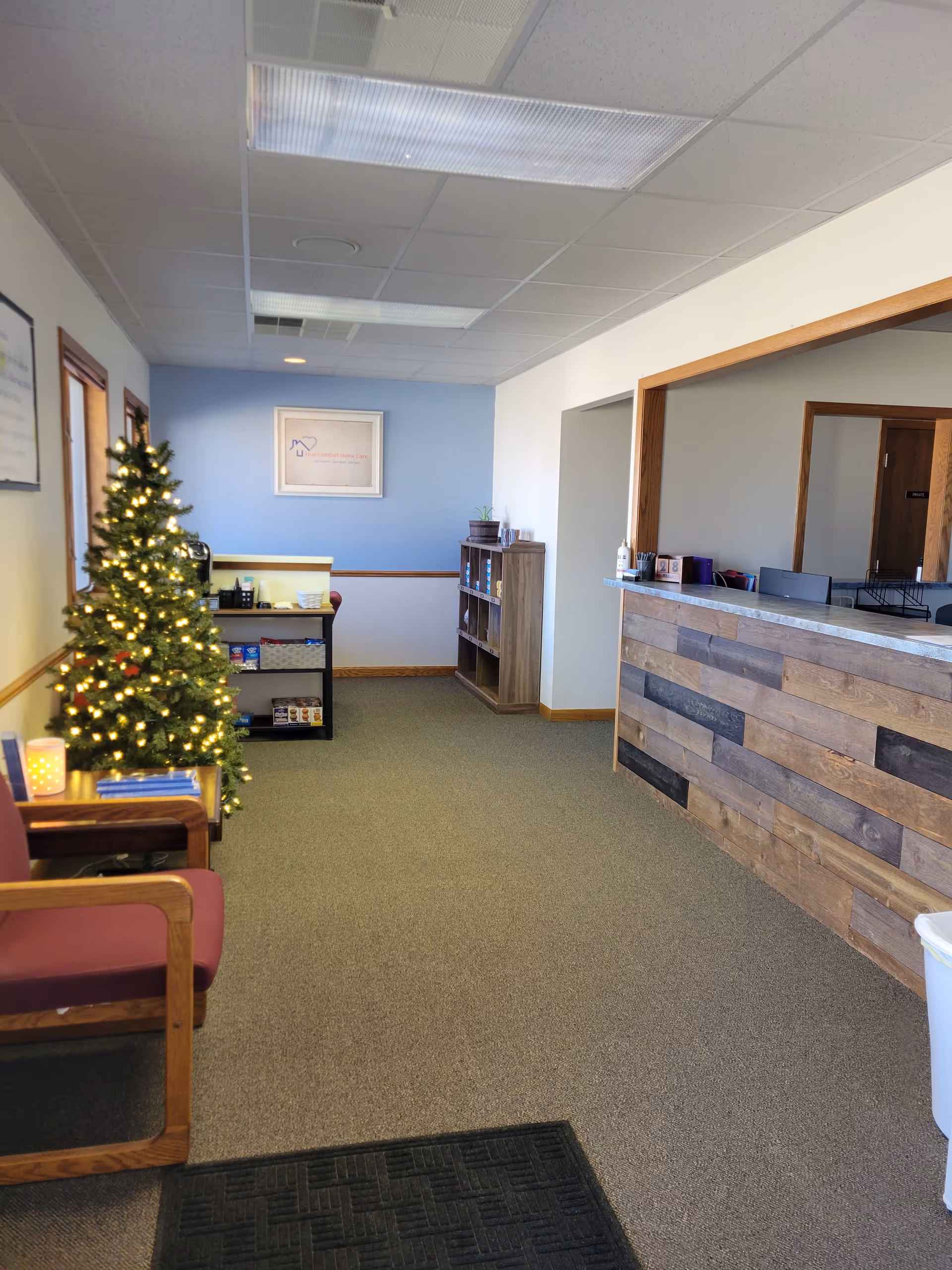Reception lobby with a wooden desk, Christmas tree, chairs, and blue accent wall.