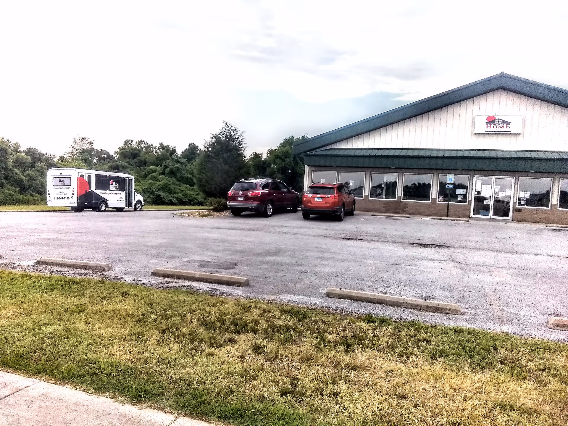 Exterior view of a Help at Home senior living building with parked cars.