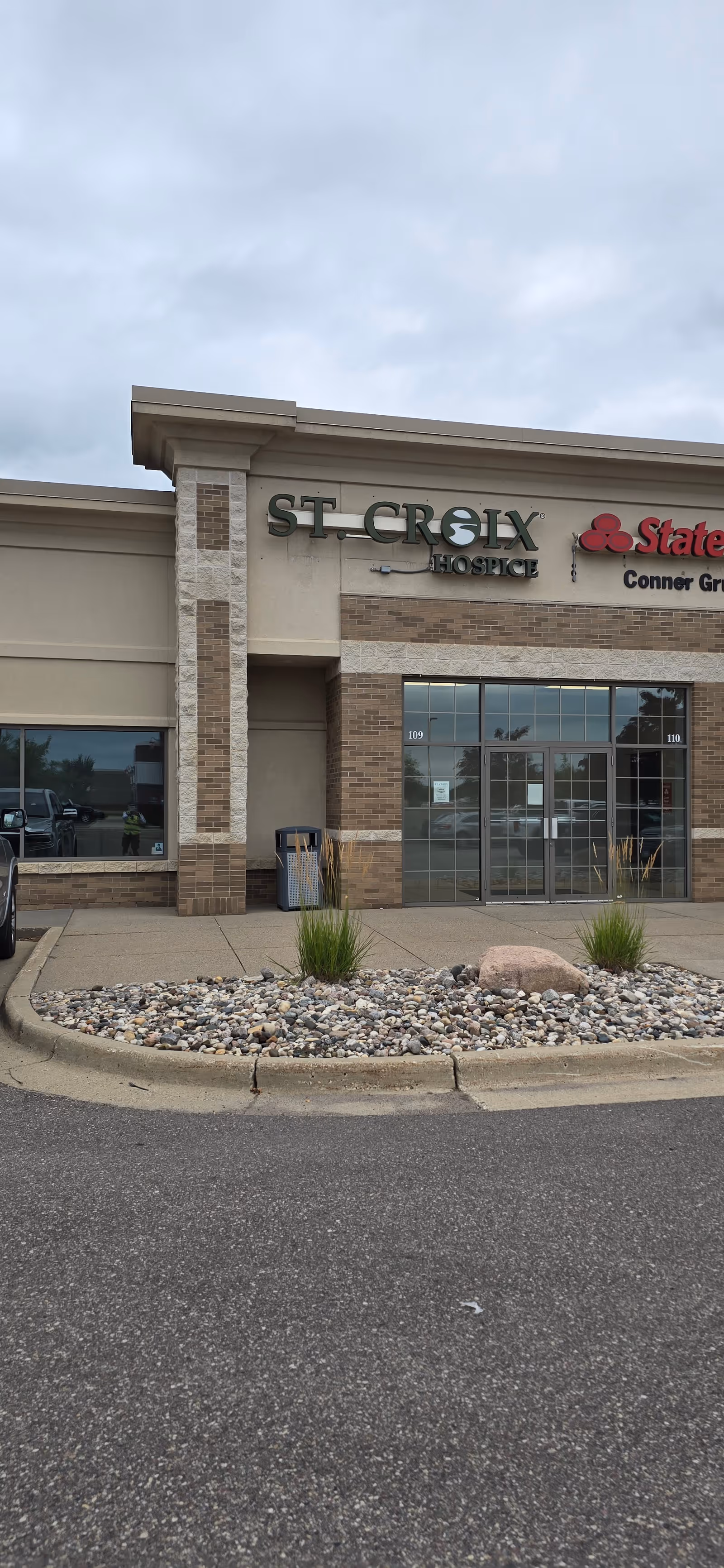 Front view of a St. Croix Hospice storefront with glass entrance and rock landscape.