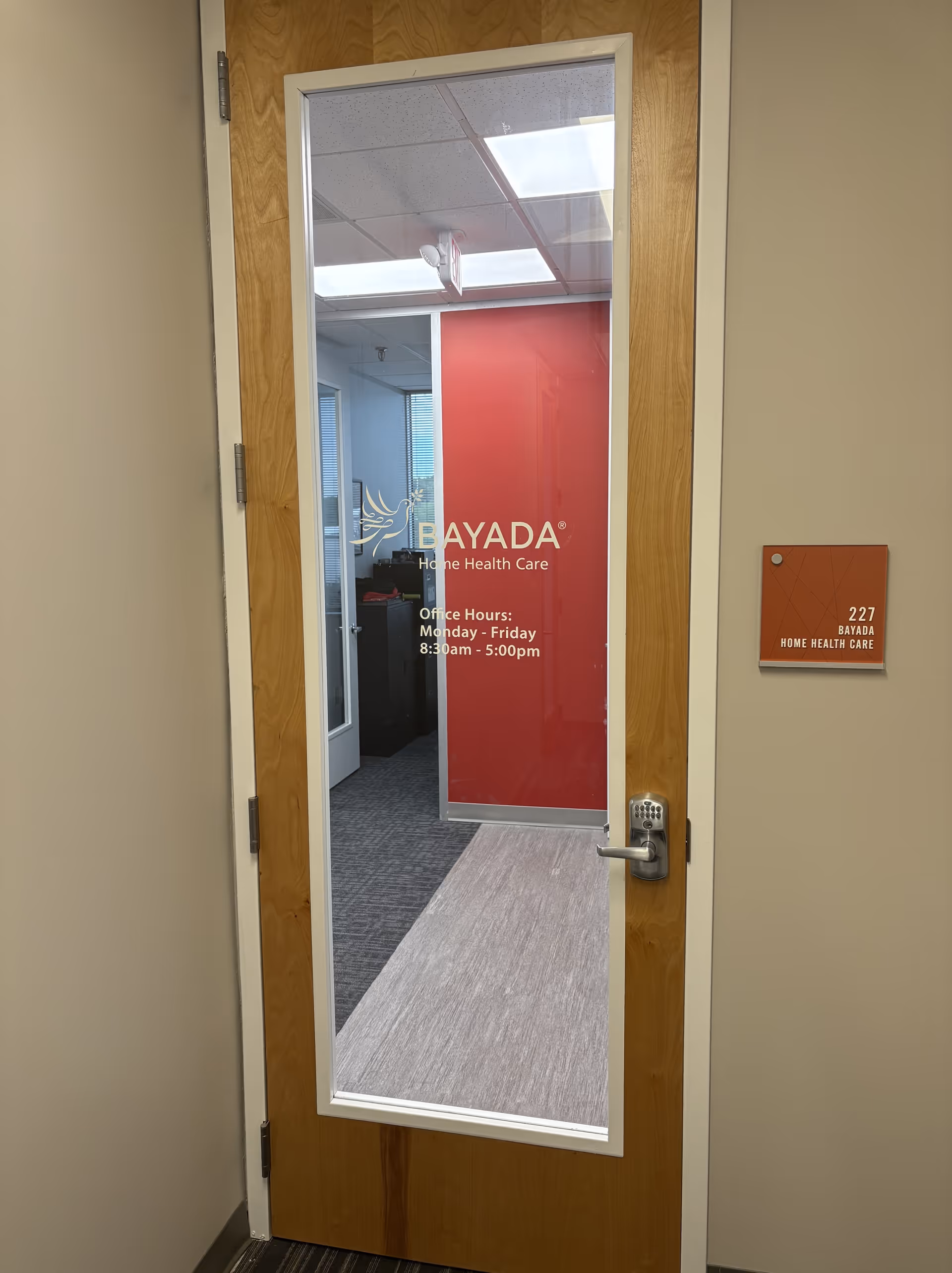 Wood-framed glass door opens into BAYADA Home Health Care office hallway.