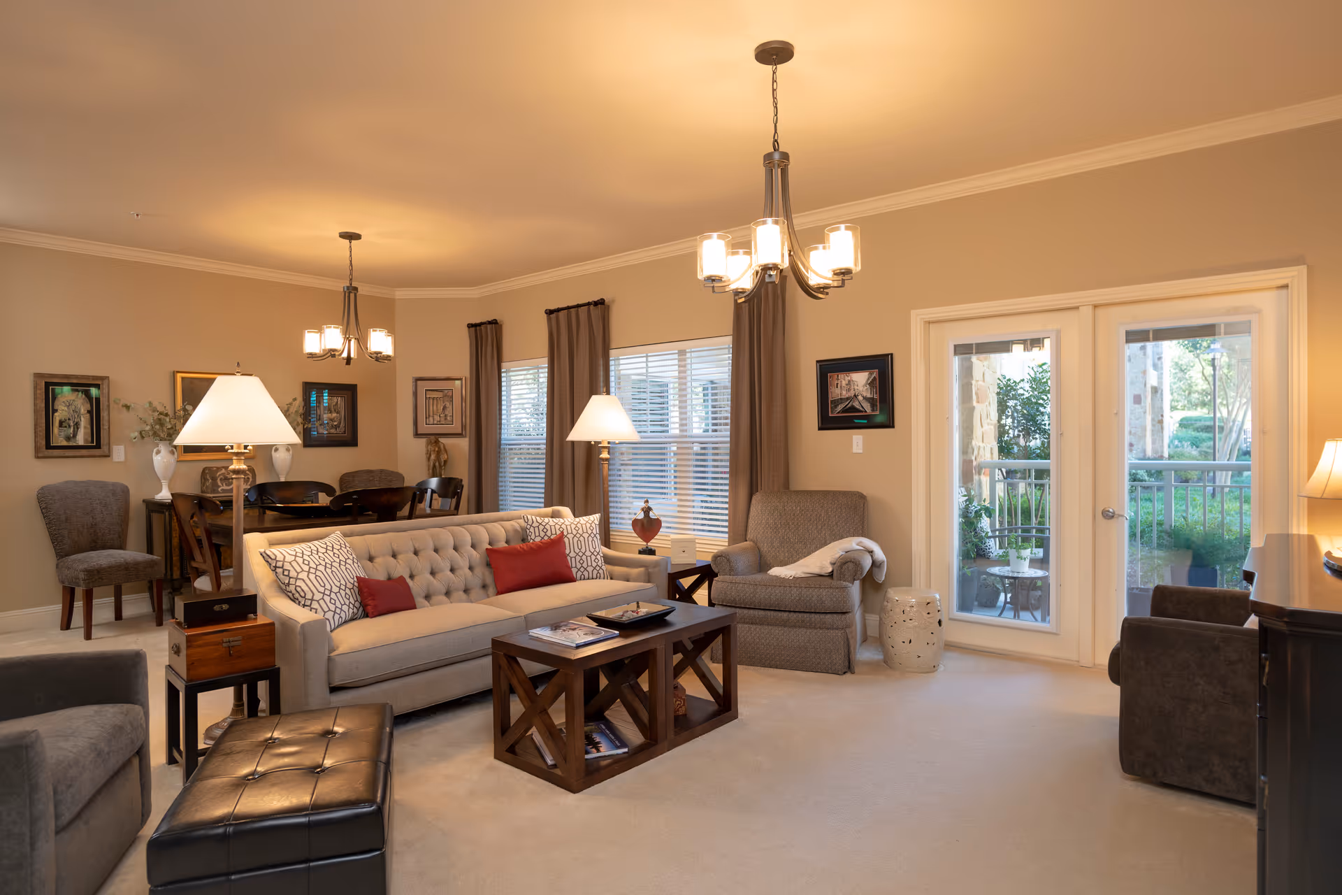 Spacious living room with beige walls, sofa, chairs, coffee table, and French doors to outdoors.