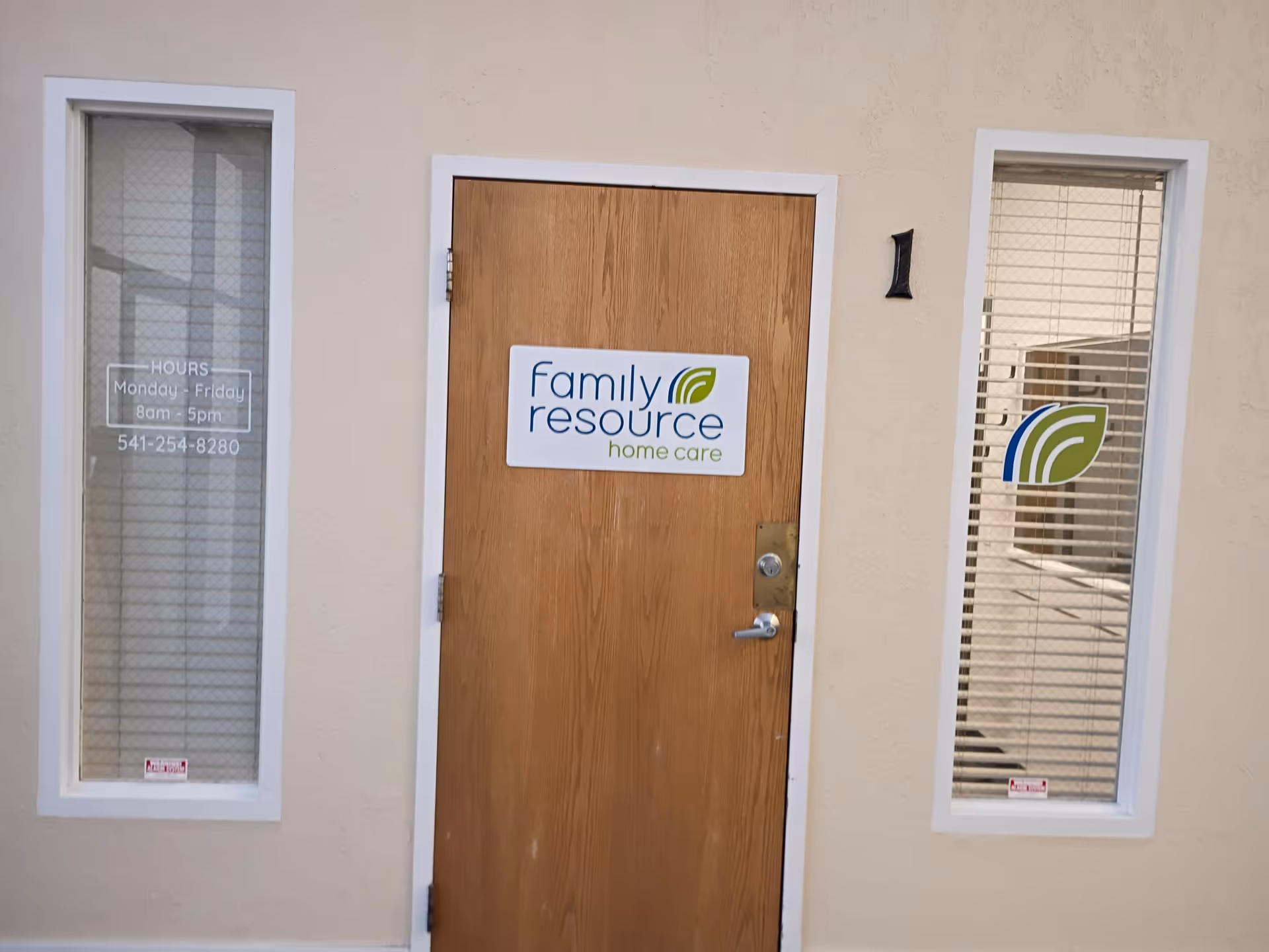 Wooden front door with Family Resource Home Care sign between two glass windows.