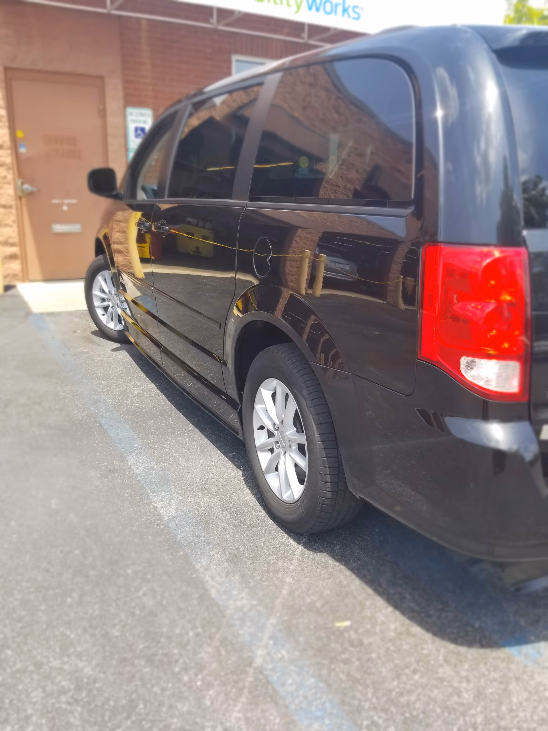 Black van parked outside MobilityWorks facility beside brick building.