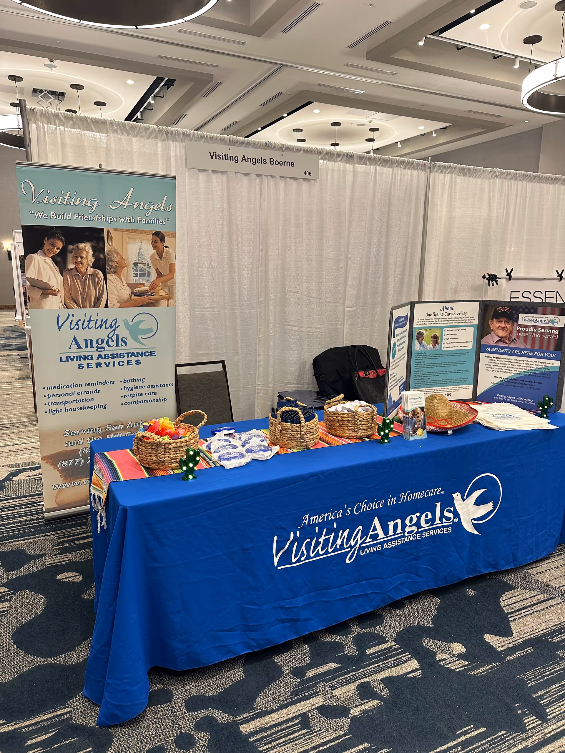 Indoor Visiting Angels booth with a blue tablecloth and promotional banners.