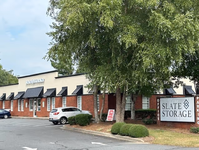 Exterior view of a brick storage facility with Slate Storage sign and trees