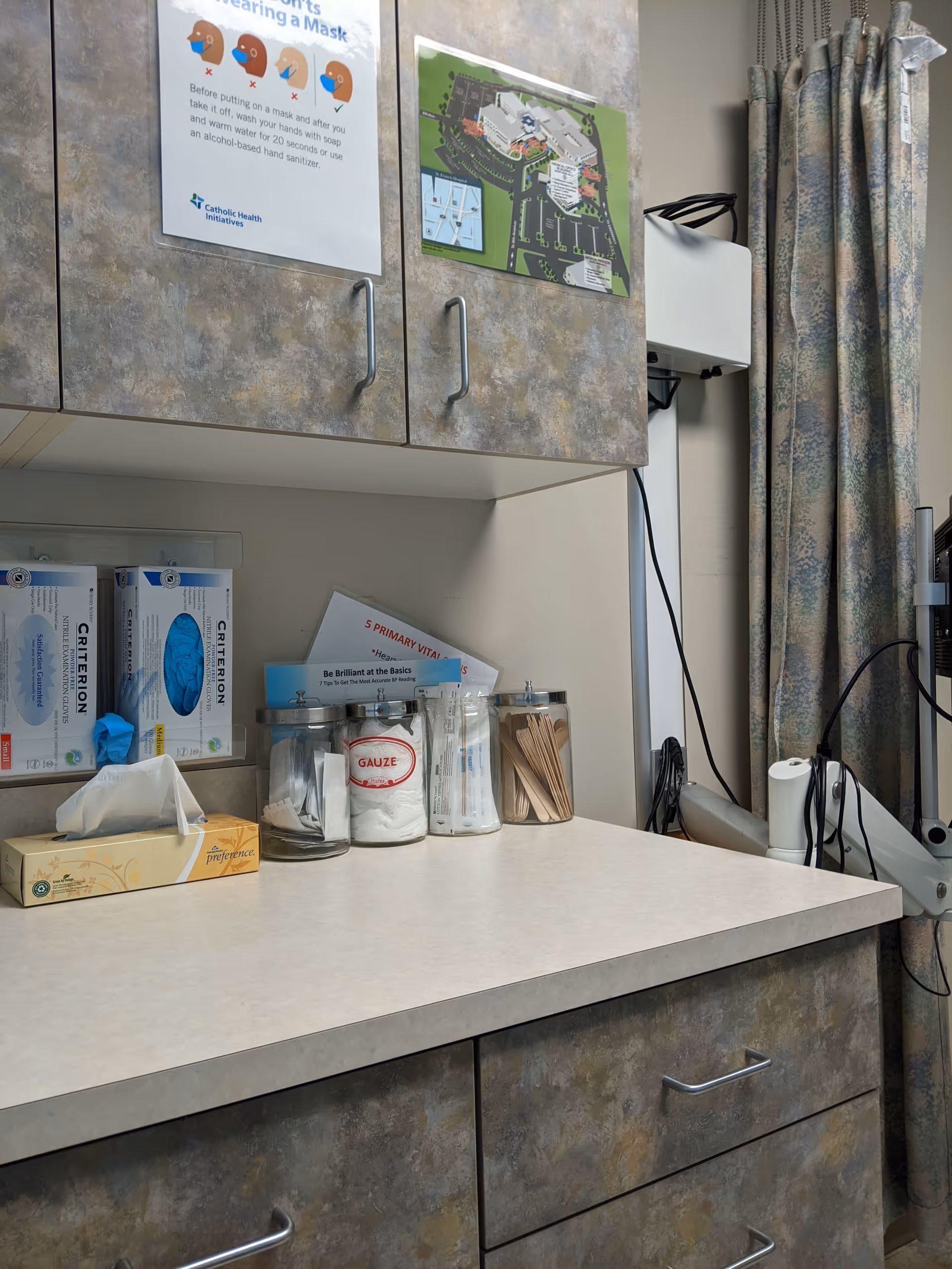 Interior hospital supply counter with cabinets, gauze, tissues, and a curtain.