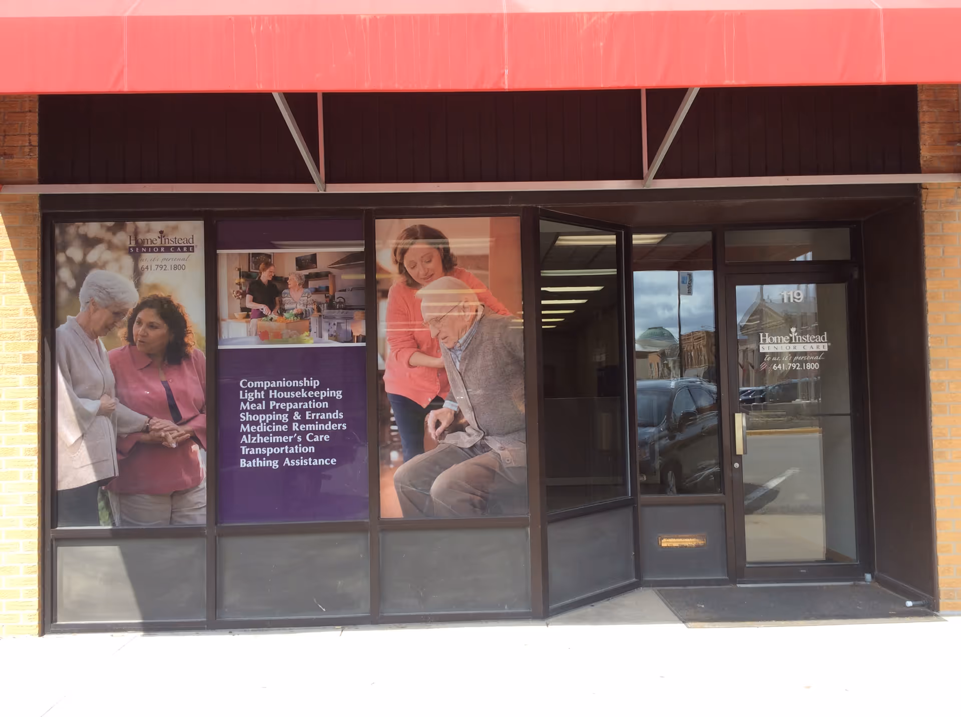 Exterior storefront of Home Instead Senior Care with large posters in windows under a red awning.
