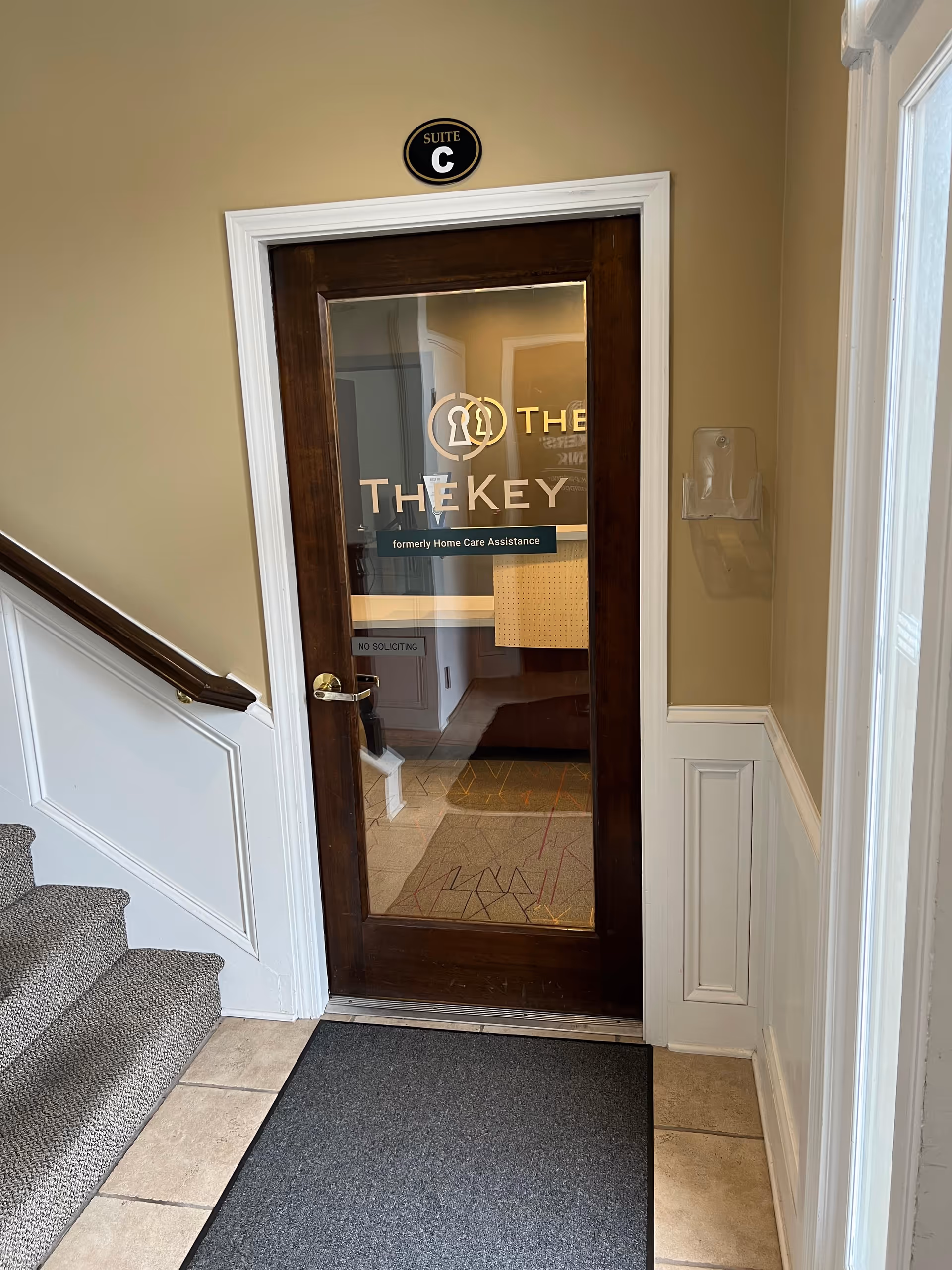 Interior hallway with a glass-paneled door labeled TheKey Suite C near stairs