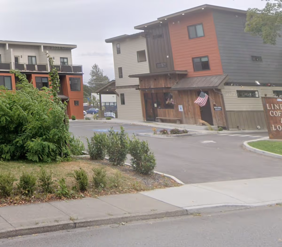 Exterior view of a multi-story senior living building with wood siding and a parking lot.