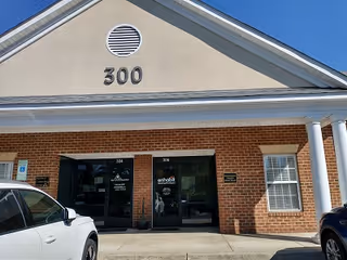 Front entrance of Enhabit Home Health facility with brick exterior and parked cars.