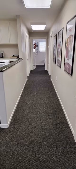 Narrow hallway in a senior living facility with framed posters along the walls.