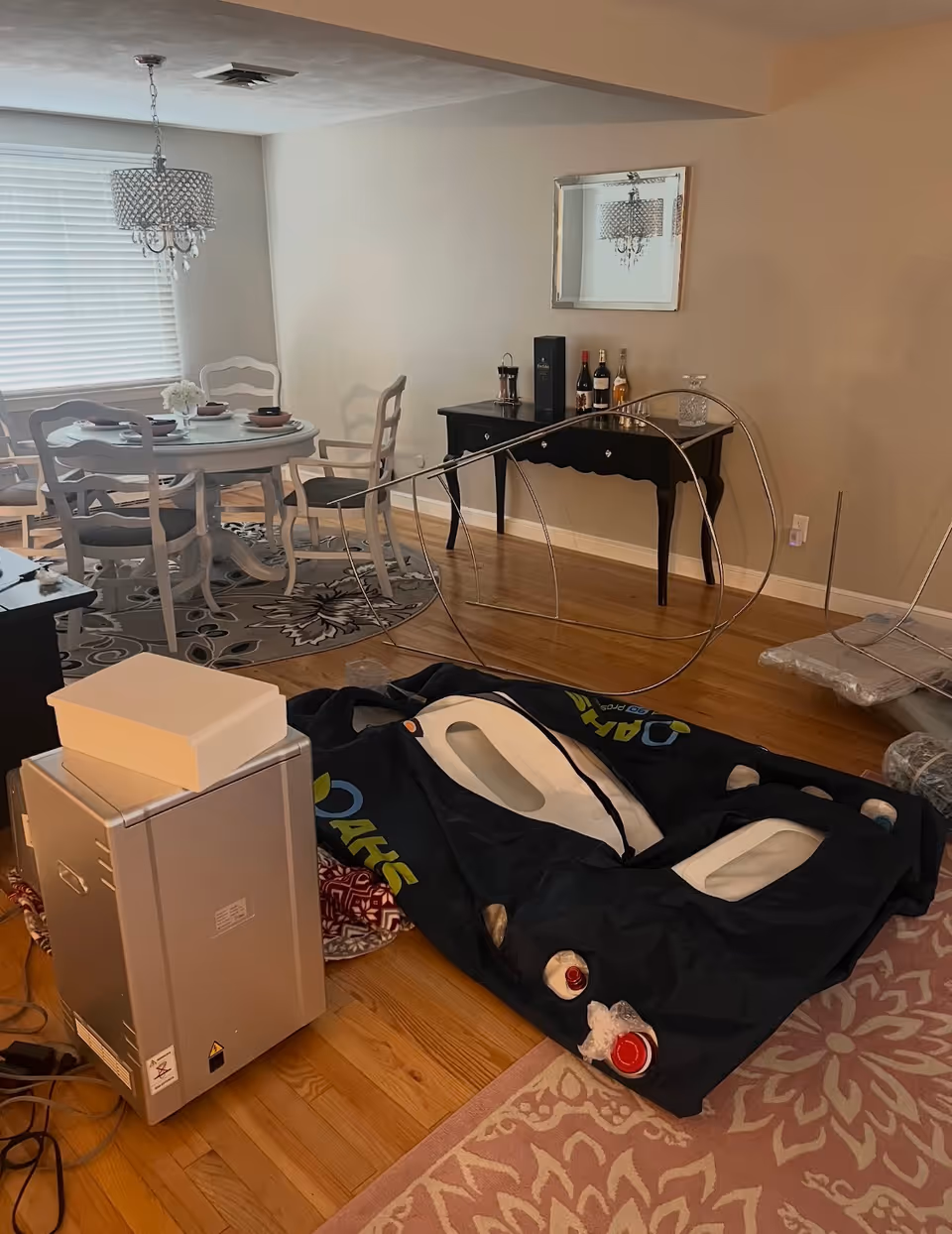 A dining area with a round table, chairs, chandelier, and medical equipment.