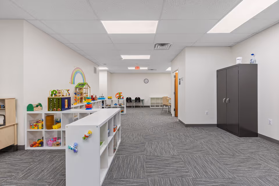 An airy interior shows a children's play area with colorful shelves and toys.