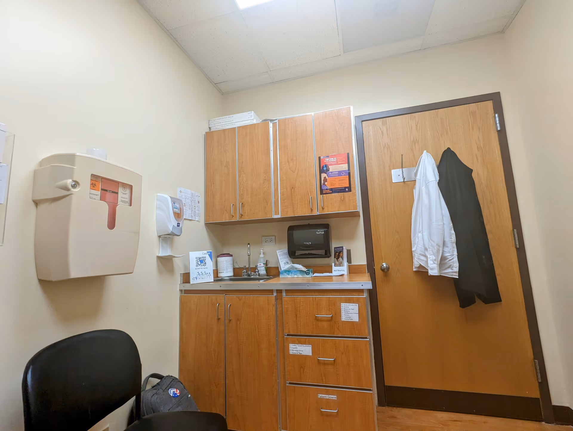 Interior clinic room with wooden cabinets, a sink, and medical equipment.