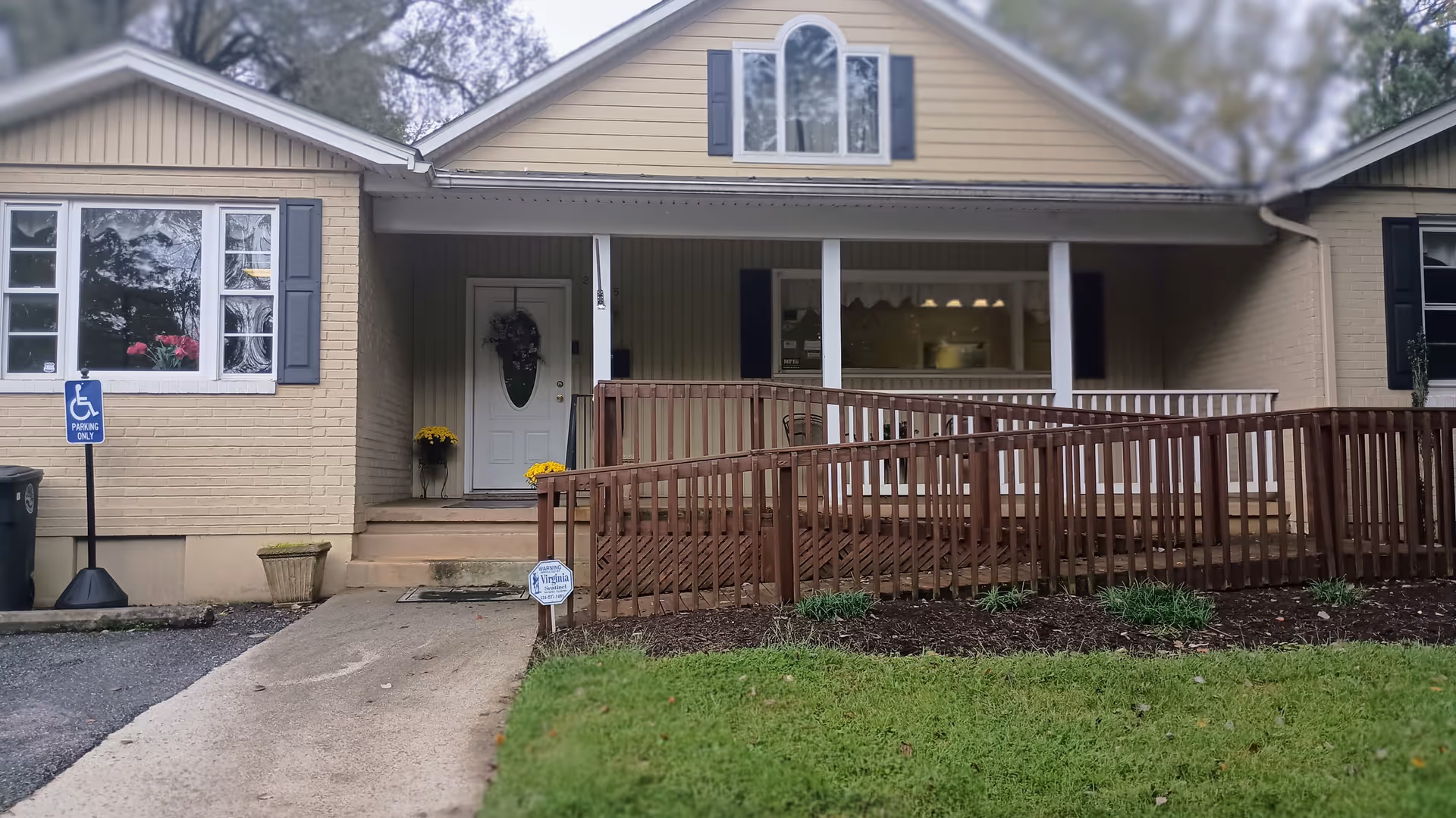 Front exterior of a single-story senior care facility with a wooden ramp and steps.