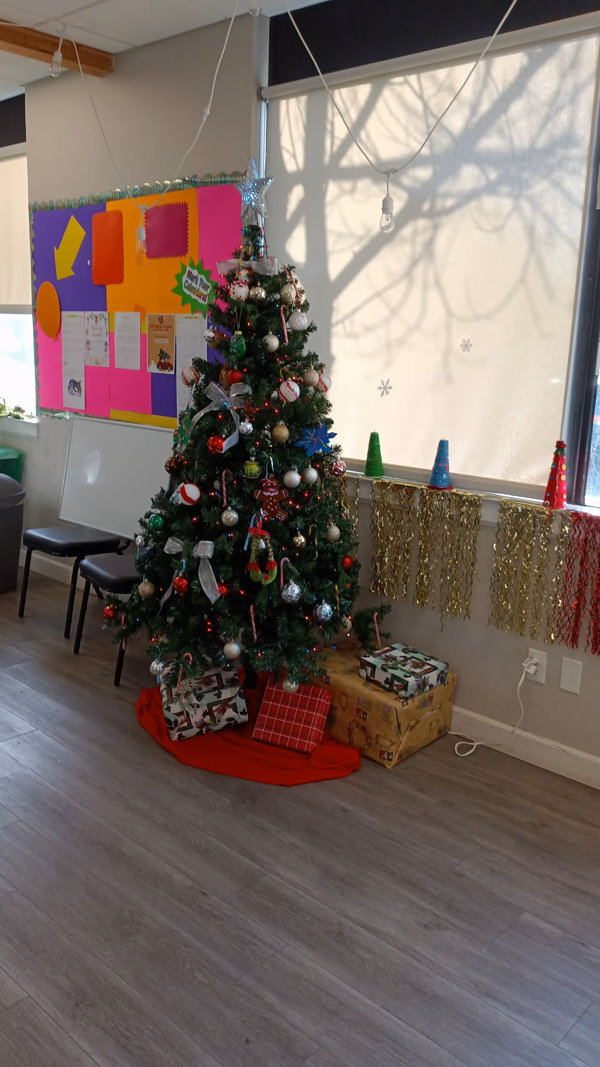 Interior common area with a decorated Christmas tree and wrapped gifts.