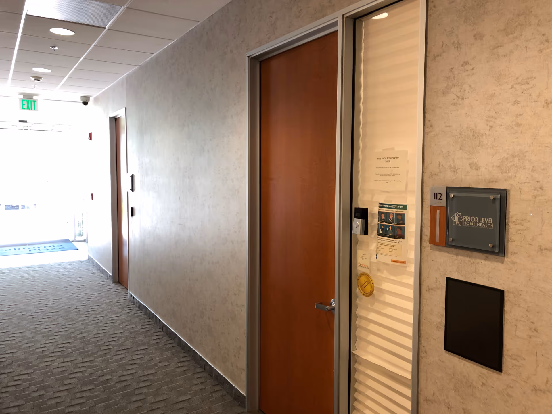Long hallway in a senior living facility with closed doors and Prior Level Home Health sign.